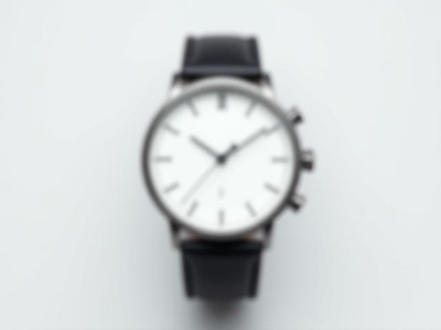 Sleek minimalist men's chronograph watch with a clean white dial and black strap.